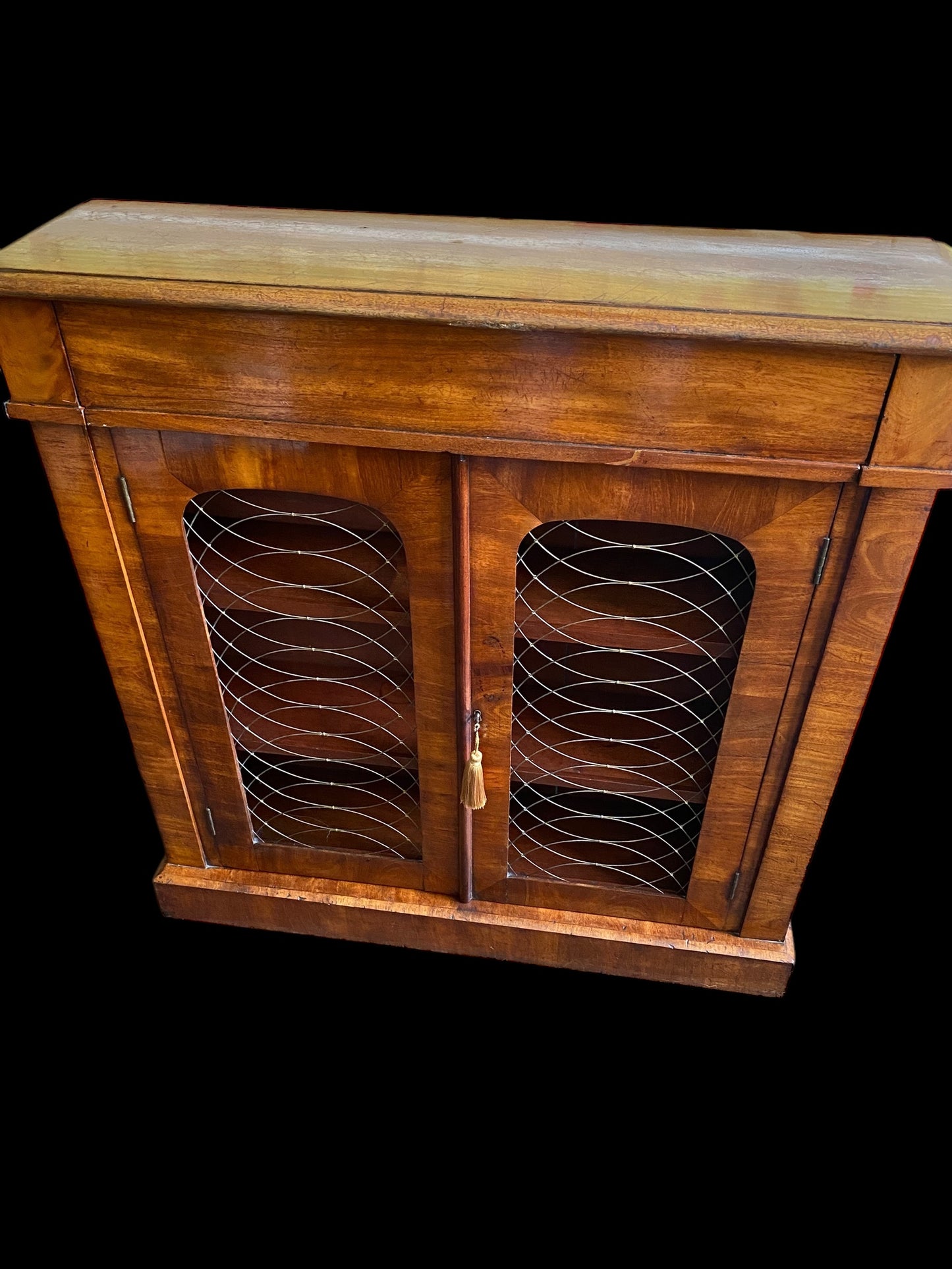 A rich walnut double door bookcase with single frieze drawer over wire mesh doors