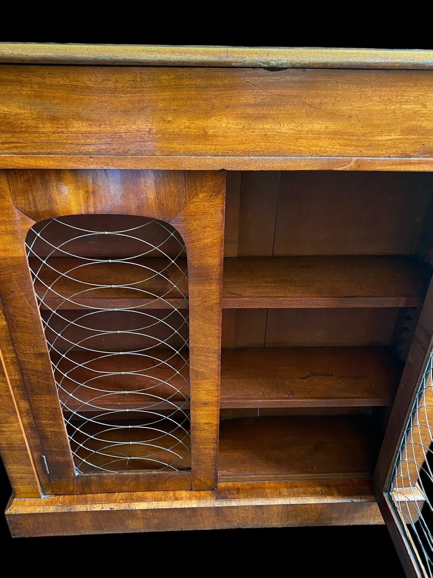 A rich walnut double door bookcase with single frieze drawer over wire mesh doors