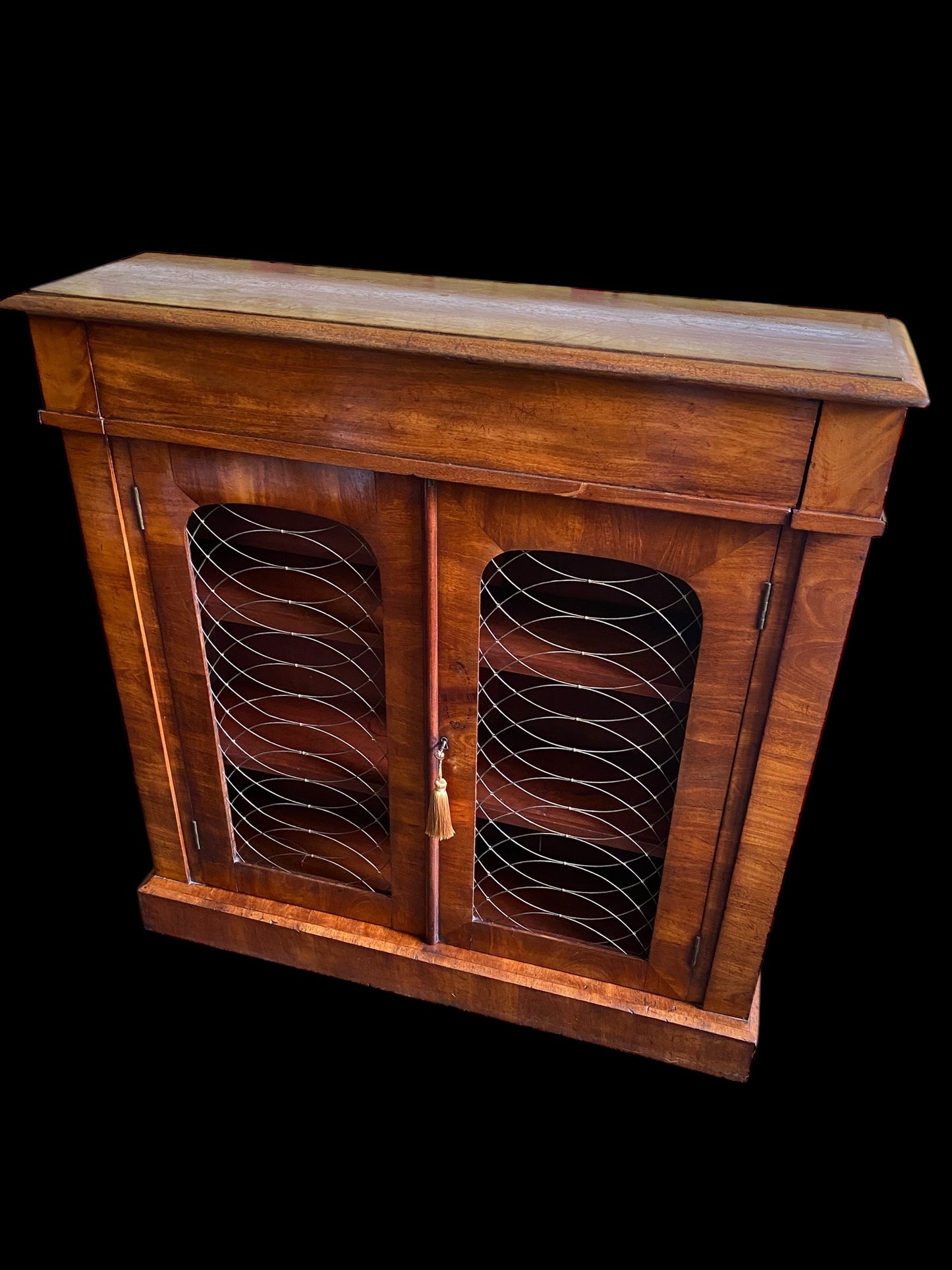 A rich walnut double door bookcase with single frieze drawer over wire mesh doors
