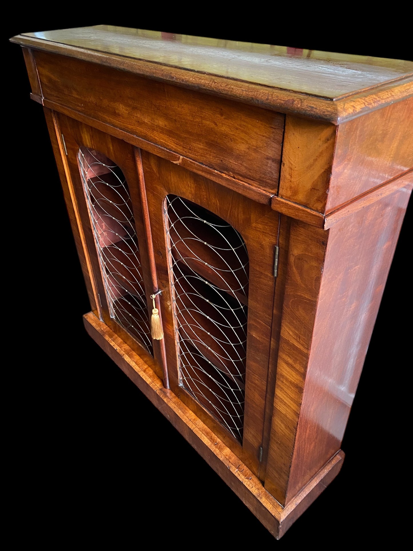 A rich walnut double door bookcase with single frieze drawer over wire mesh doors
