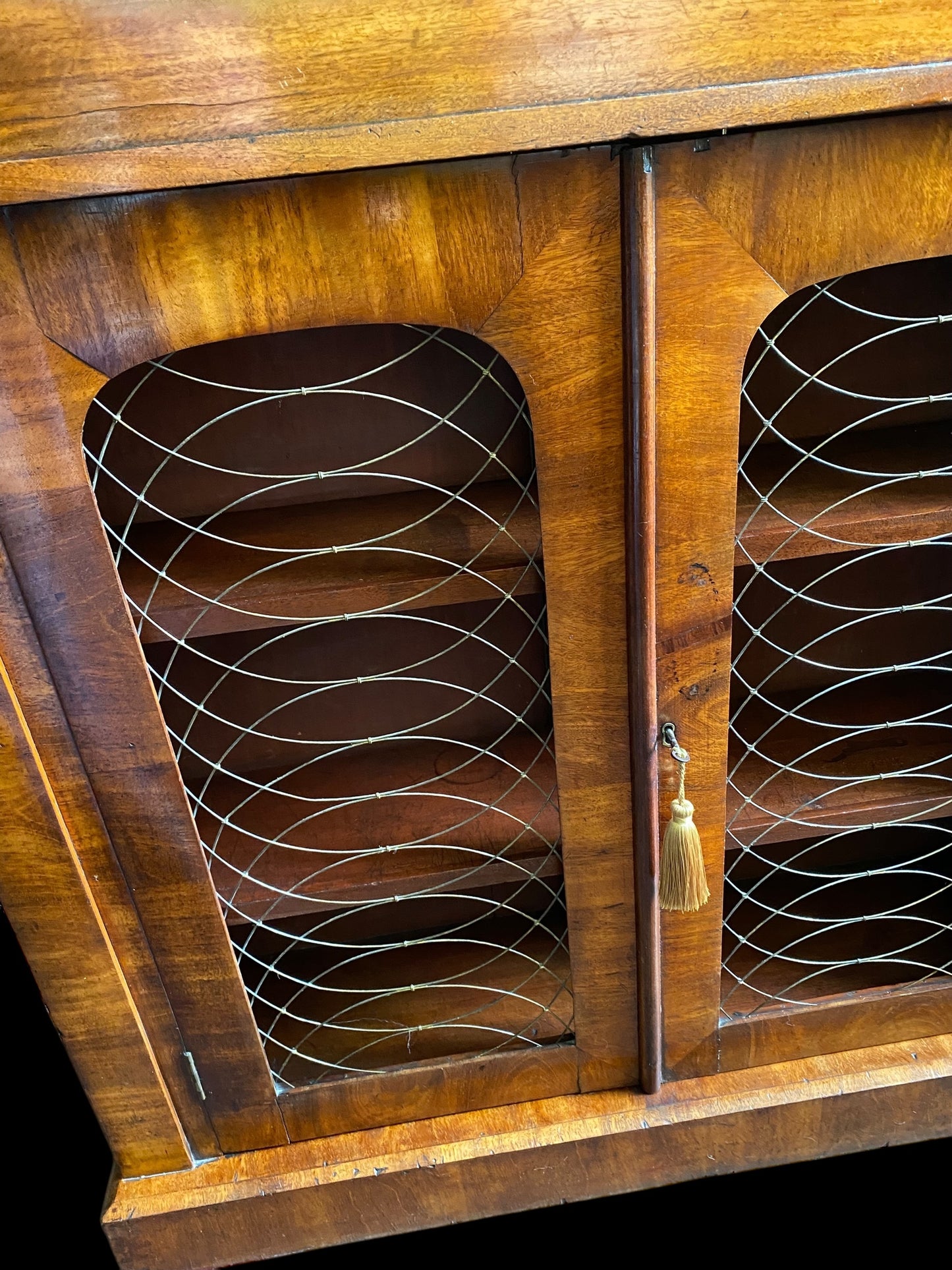 A rich walnut double door bookcase with single frieze drawer over wire mesh doors