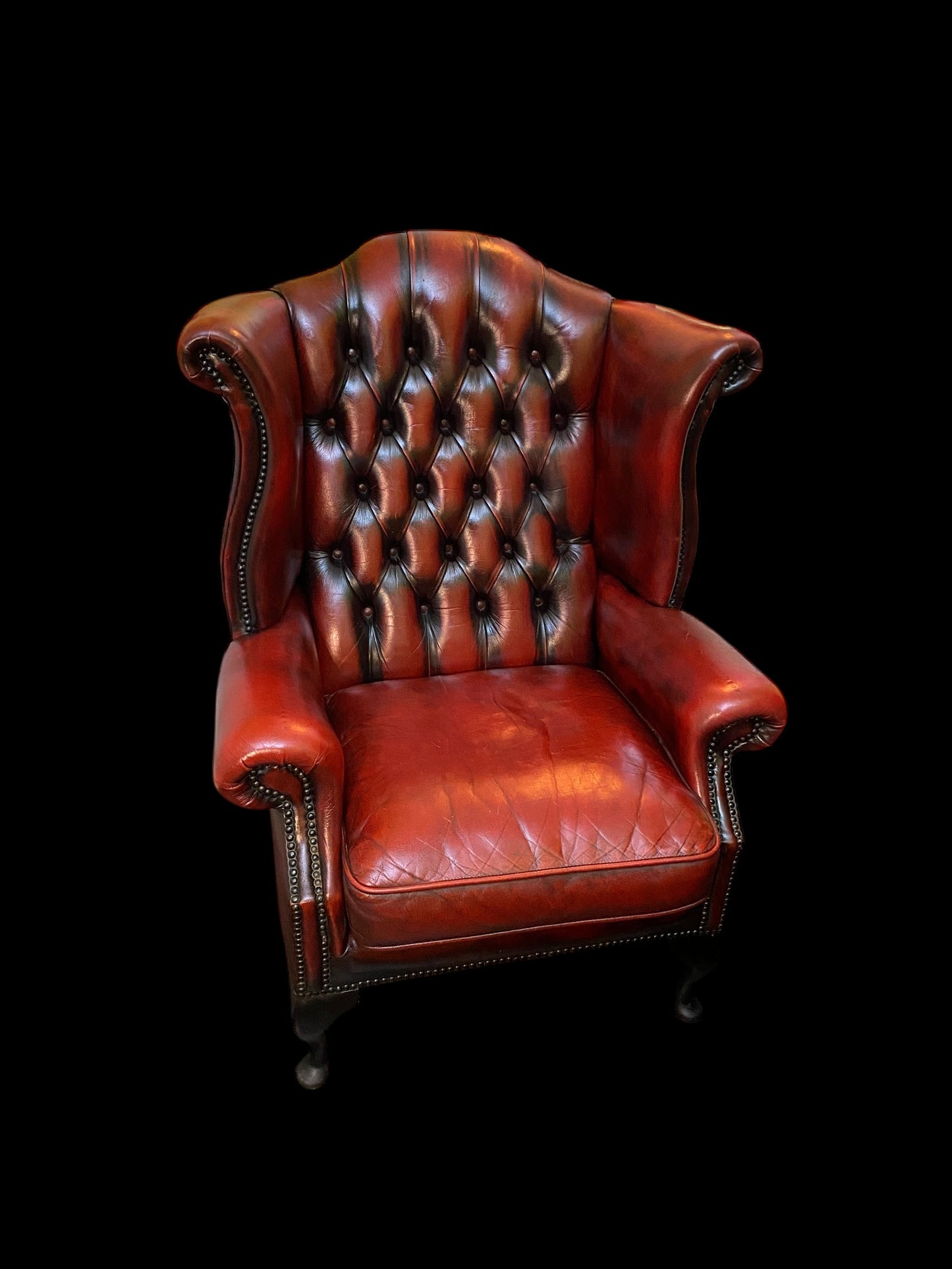 A sumptuous oxblood leather buttoned wingback armchair